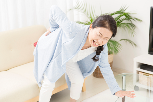 腰に痛みを感じる女性