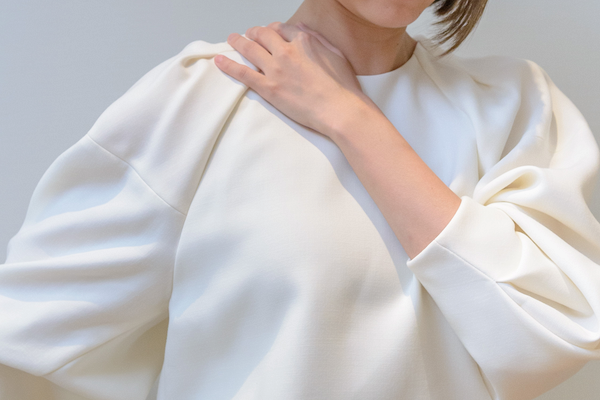 痛みで首元を押さえる女性